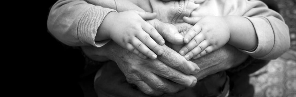 elderly hands hold young child